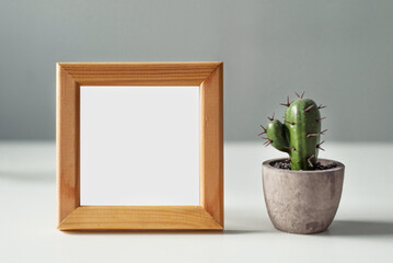 Empty mockup of a wooden frame with a cactus in a pot: a fragment of the interior for your painting, photo, poster, motivation quote