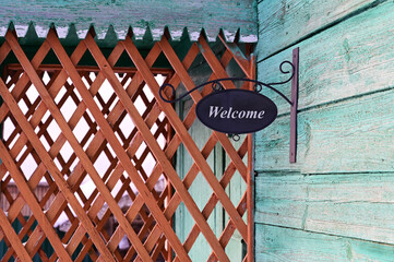 sign "Welcome" at the entrance to the wooden house