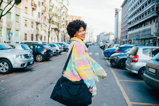 Young black woman traveller walking outdoors city holding duffel bag