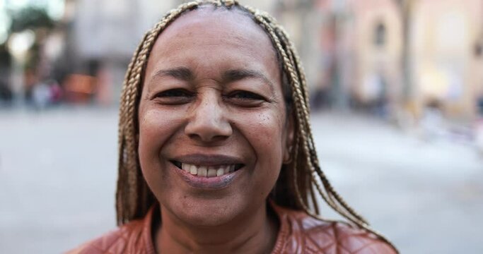 Senior african woman smiling on camera with city on background