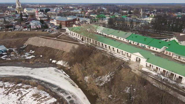 Frozen river, ice melts, on the bank of a small town. Spring, snow melts, dry grass, flood and river flood. Day, cloudy weather, soft warm light. UHD 4K