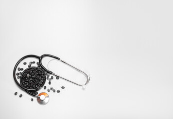 Coffee beans on white background next to stethoscope or phonendoscope: place for text, high blood...