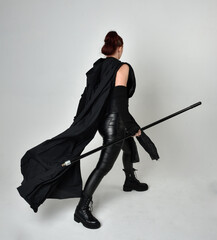 Full length portrait of pretty redhead female model wearing black futuristic scifi leather costume,...