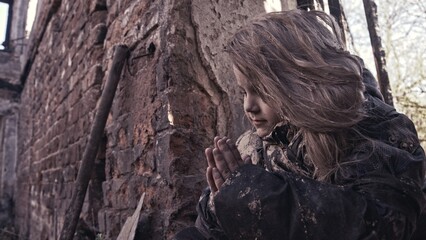 girl praying. Children without a home, apocalypse, war