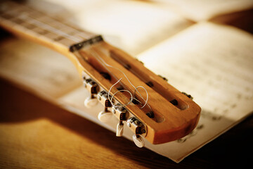 The fretboard of an old vintage acoustic guitar with metal strings lying on a wooden table next to...
