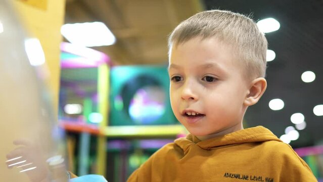 Boy playing on the kids game machine at an amusement park. Child playing on the kids game machine.