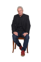front view of a man sitting  on chair with sneakers jeans and blazer on white background