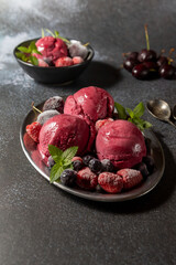 Homemade blueberry ice cream scoops with fresh berries and mint leaves in cups over light blue background, selective focus