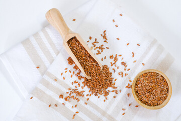Flax seeds in a round plate with wooden spoon on a linen napkin in a kitchen. Ingredient for flaxseed porridge and jelly. Minimalistic simple natural light template. Superfood. Organic eco healthcare.