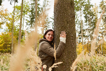 Woman forest bathing in nature hugs a tree