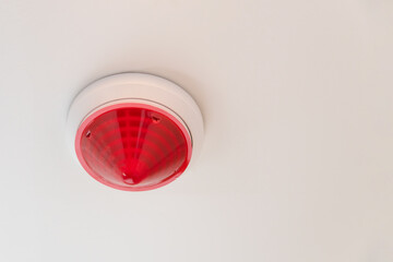 Red round smoke detectors on the ceiling for security and fire alarm systems, copy space