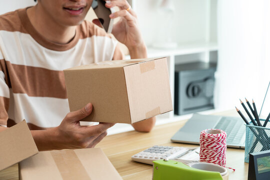 Online shopping concept a retailer holding a parcel post while talking with his customer on the mobile phone