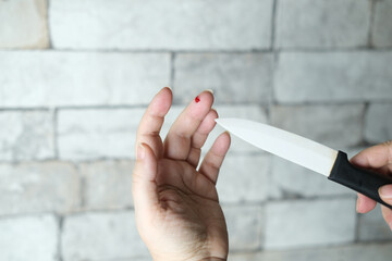 drop of red blood, close-up of female hand, wound on the finger from a cut, a kitchen knife with a...