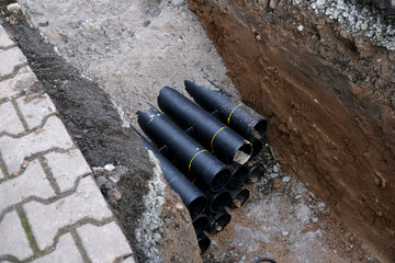 lot of new black pipes for protecting electrical wires in trench on street, concept of repairing...