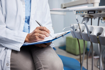 I recommend a daily dose of good dental hygiene. Shot of an unrecognisable dentist writing notes on...