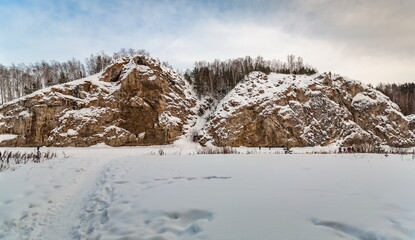 Winter landscape with a big stone, forest, sky from a frozen river