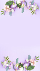 Fototapeta premium Floral frame with pink roses, white flowers, branches, leaves and petals on purple background. Flat lay, top view