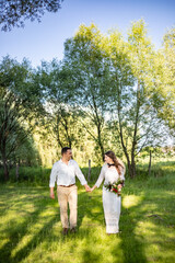 Happy young people in wedding attire walk in the meadow and look at each other