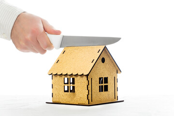 Kitchen knife in hand cutting a house model in half