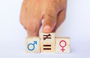 Hand picks up a wooden cube with symbols of woman, man and equals on colored background. feminist concept equality in society