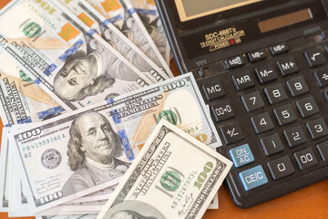 Fototapeta premium Calculator and 100 dollars on wooden table.