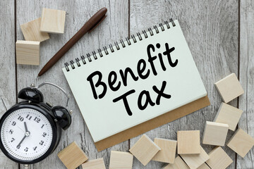 TAX BENEFITS text on paper from notepad near table clock