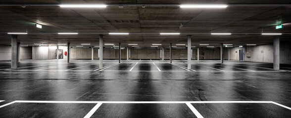 Front view of new empty underground parking with concrete columns, shiny asphalt and nobody inside - obrazy, fototapety, plakaty