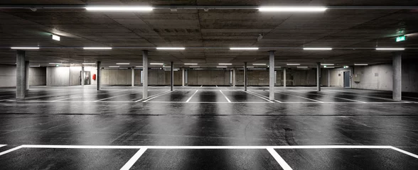 Fototapeten Front view of new empty underground parking with concrete columns, shiny asphalt and nobody inside © alexandre zveiger