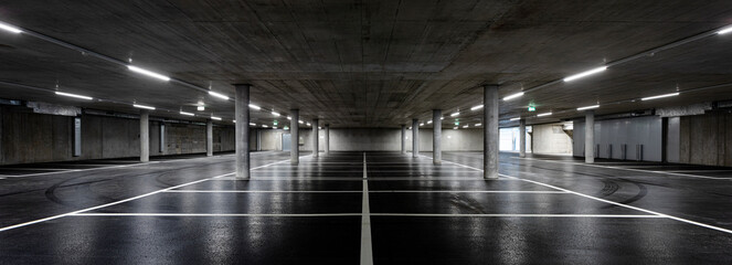 Front view of new empty underground parking with concrete columns, shiny asphalt and nobody inside