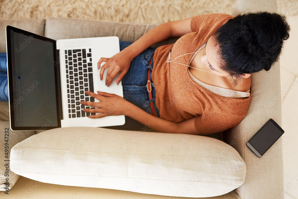 Poster Catching up with my social networking. Shot of an unrecognizable woman using a laptop at home.