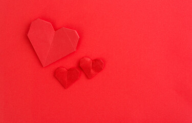 Red origami hearts on red background