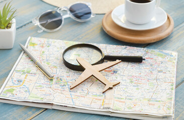 Fototapeta na wymiar Go on an adventure. The map and magnifying glass, coffee cup, wooden plane on a wooden table.