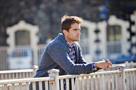 Some fresh air to clear the mind. Shot of a handsome young man leaning over a railing.