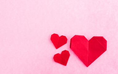 Red origami hearts on pink background.