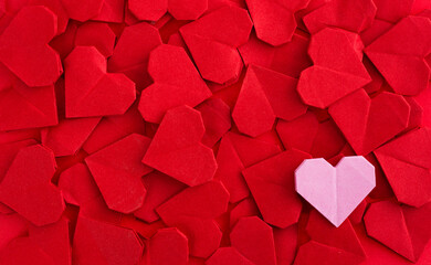 Pink origami heart on red origami hearts