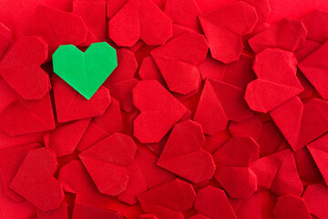 Green origami heart on red origami hearts