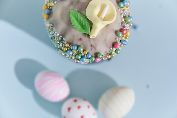 Close-up of three white Easter eggs with a pattern in the form of hearts and waves and a cake with a flower decoration. Orthodox Easter on a blue background top view. High quality photo