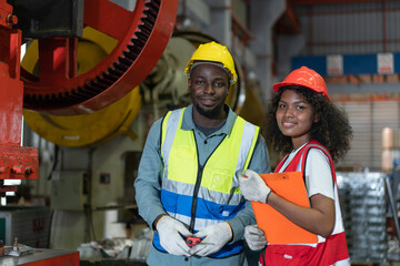 Portrait of African American male and female worker wearing safety vest with helmet smiling look at camera while working in factory