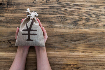 Hands holding a money bag with Chinese yuan sign