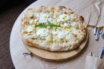 Roman round pizza five or four cheeses on a round wooden kitchen pizza board. Delicious fresh...