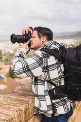 Chico gordo tomando fotografías con cámara en pueblo blanco andaluz