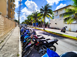 Many bikes parked on the beatiful street with palms, Mexico
