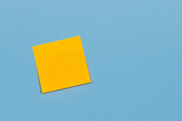 Yellow paper adhesive note stuck to a blue background.