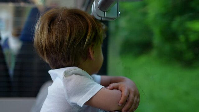 Small boy looking out train window traveling