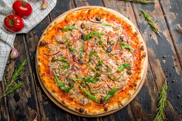 Pizza with tuna and red onion on old wooden table top view