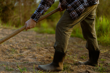 Gardening concept a male farmer using a hoe digging to the soil for making vegetable plots preparing for growing the plants