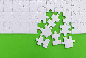 Unfinished white puzzle pieces on green background