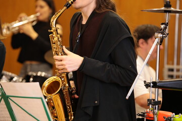 A person with a golden saxophone playing a concert on stage with drums and trumpet in a youth jazz...