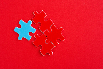 Three red and one blue puzzle pieces on red background