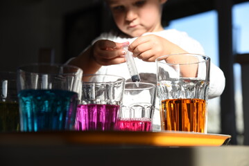 Artistic activities with autistic child. Fun with colors in kindergarten and creativity. Childhood and positive experimenting with colorful water in glasses.
